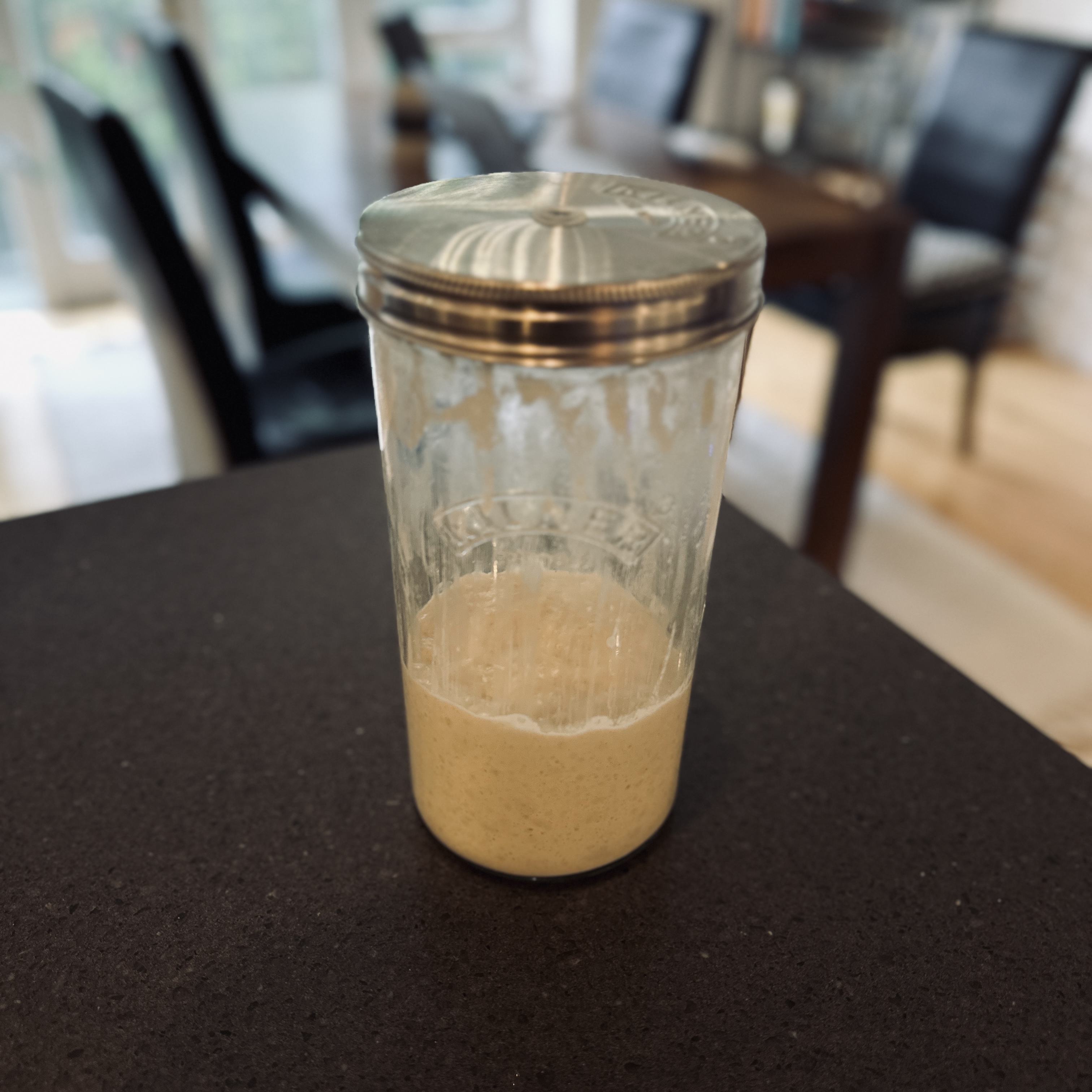 Mason jar of bubbling sourdough starter on a kitchen counter.